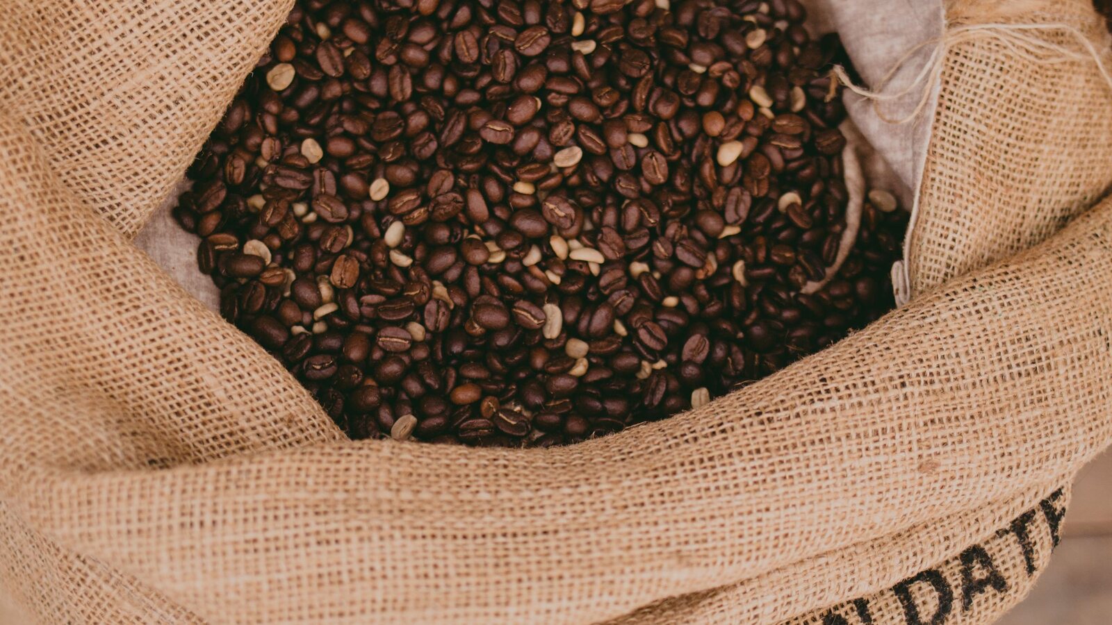 An open jute sack of freshly roasted beans.